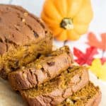 a loaf of sliced vegan pumpkin bread with pumpkin in background
