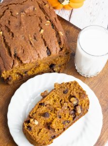 overhead photo of slice of pumpkin bread on white plate with glass of almond milk
