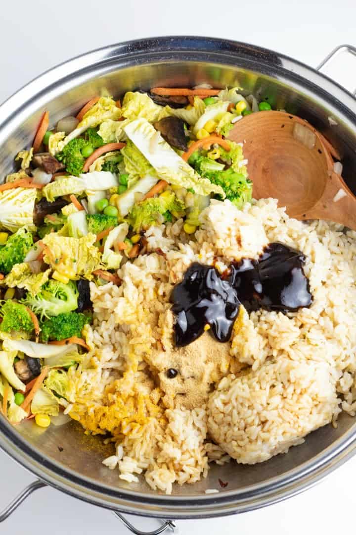 stainless wok full of veggies, rice, and brown sauce