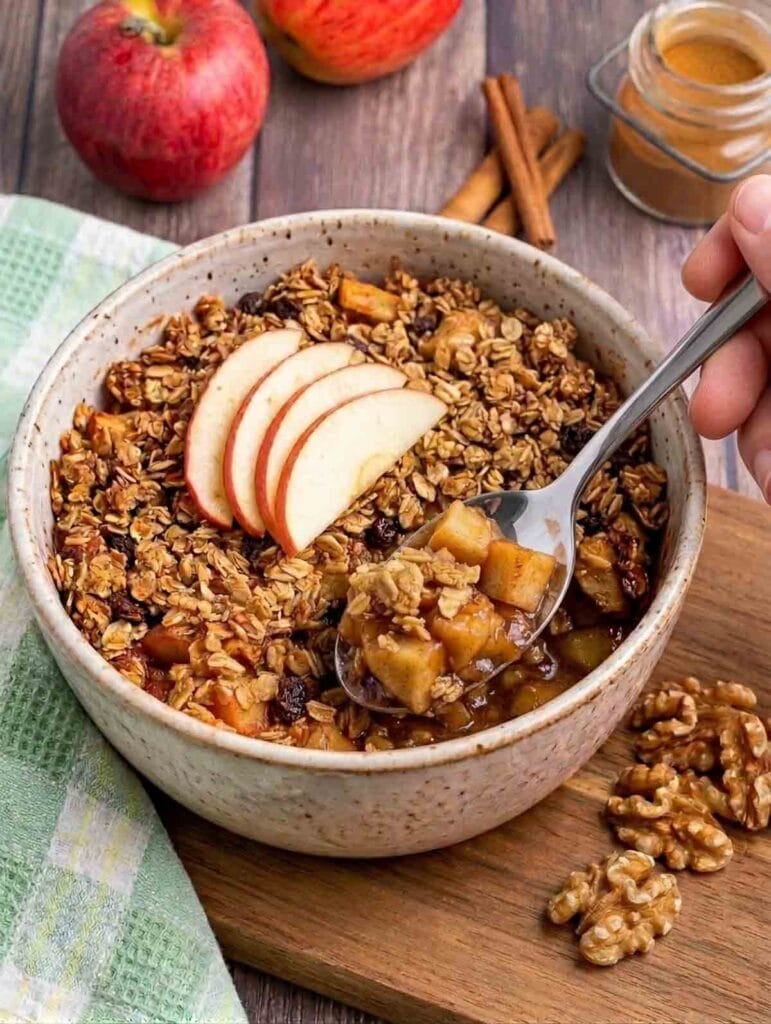 apple crumble in a crock bowl with a spoon.