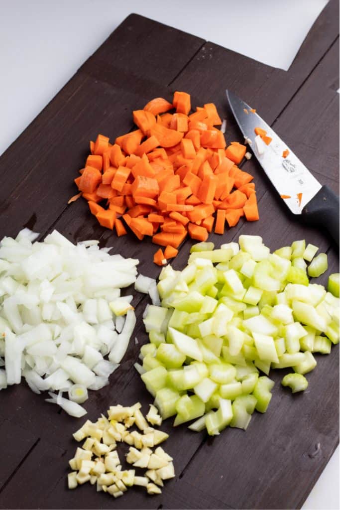 diced onions, garlic, carrots, and celery on brown cutting board