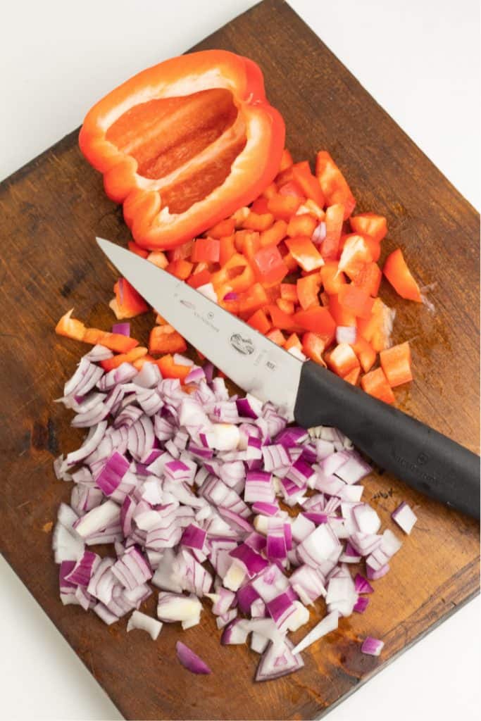 diced red bell pepper and red onion on wood cutting board