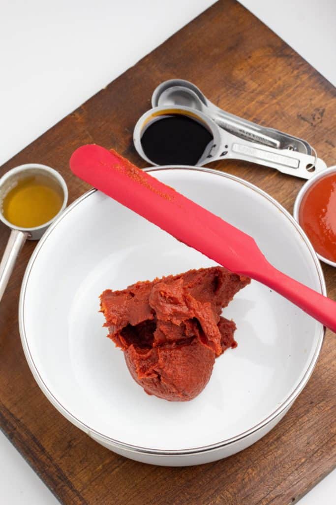 tomato paste in bowl with molasses and ketchup in measuring spoons