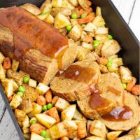 vegan roast with roasted potatoes and carrots in cast iron baking dish