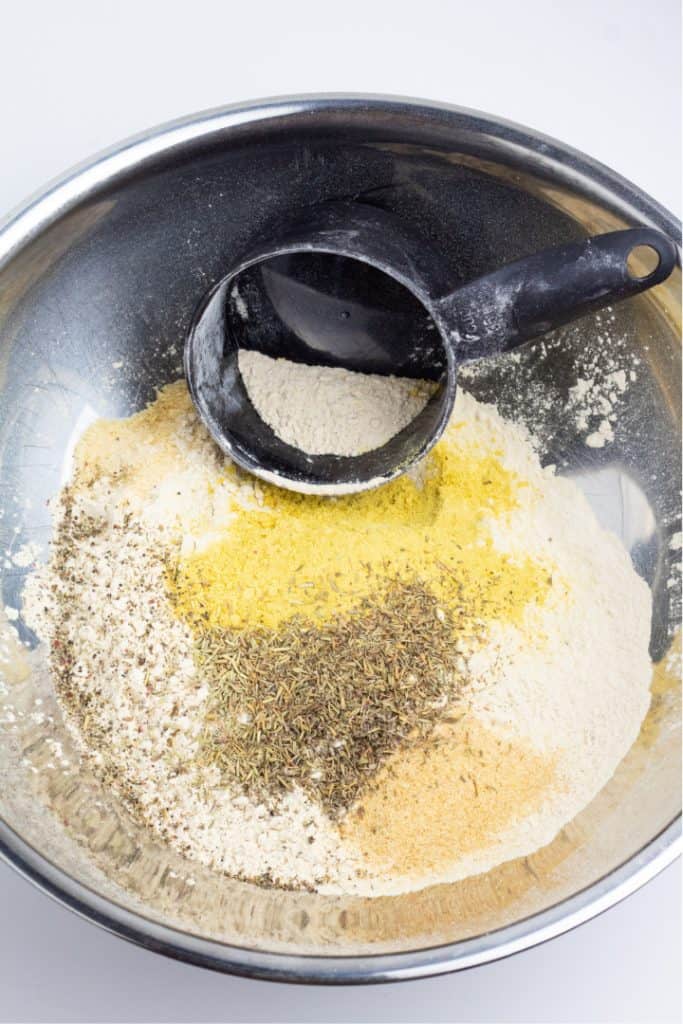 vital wheat gluten, nutritional yeast, and measuring cup in stainless bowl