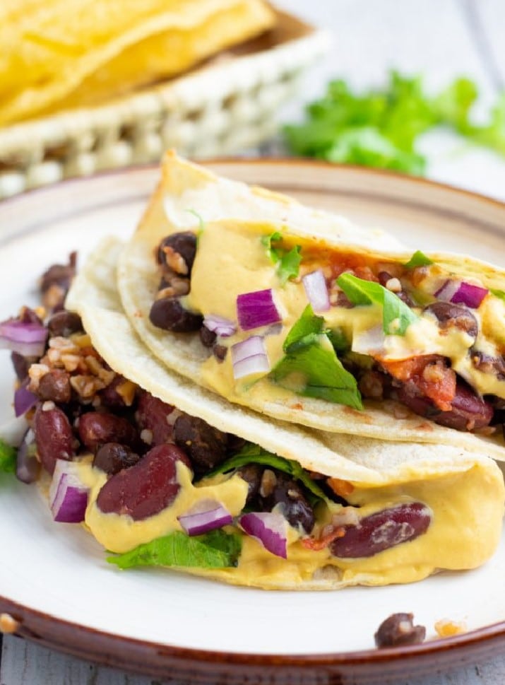 two vegan bean tacos stacked on plate
