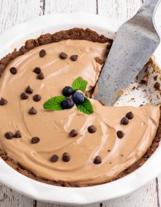 vegan chocolate pie in white pie dish with pie cutter