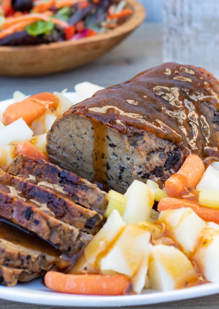 vegan seitan mushroom roast on platter with potatoes and carrots