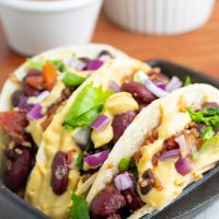 3 tacos stuffed with vegetables and standing in black cast iron pan