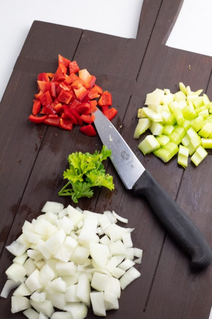 diced onion, celery, celery on brown cutting board with knife