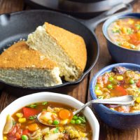 3 bowls of vegetable soup with instant pot and cornbread in background