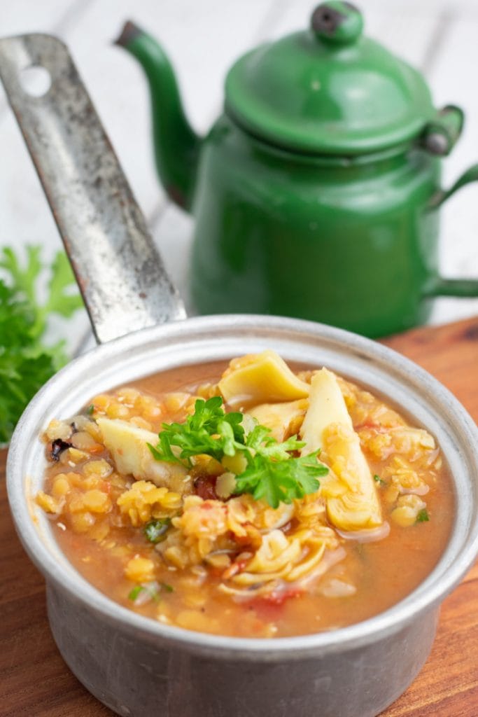 lentil artichoke stew in tin pot with green kettle in background