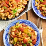 overhead photo of mac chili in bright blue plates and cast iron pan on wooden tabletop