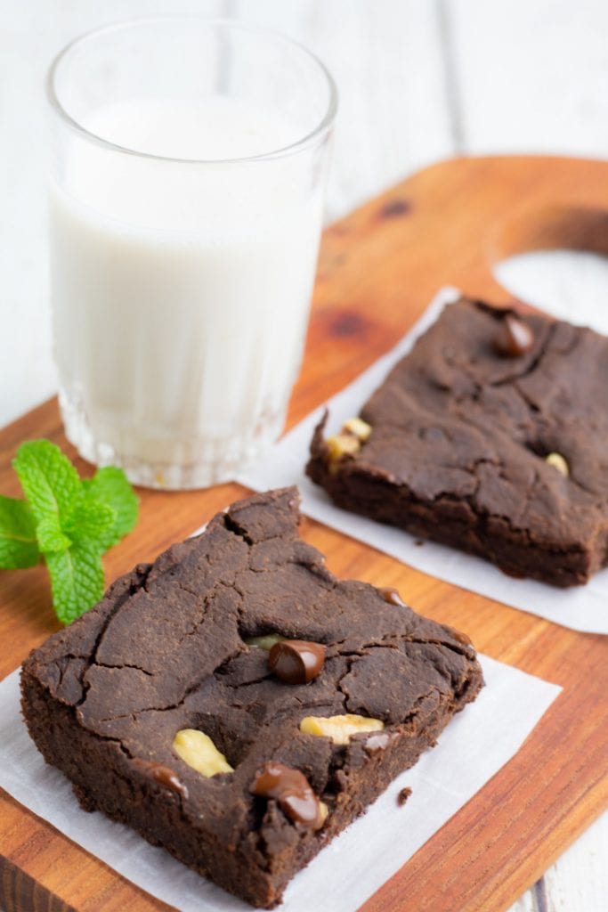 vegan black bean brownies on cutting board with glass of almond milk