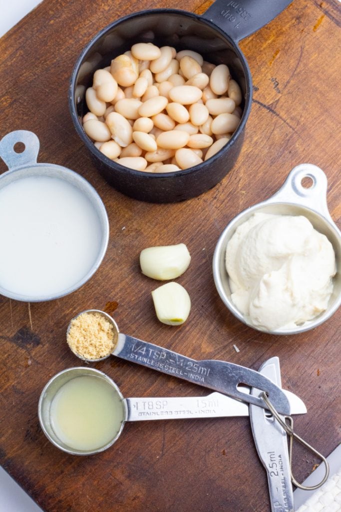 white beans, almond milk, vegan mayo, garlic, and spices on dark wood cutting board