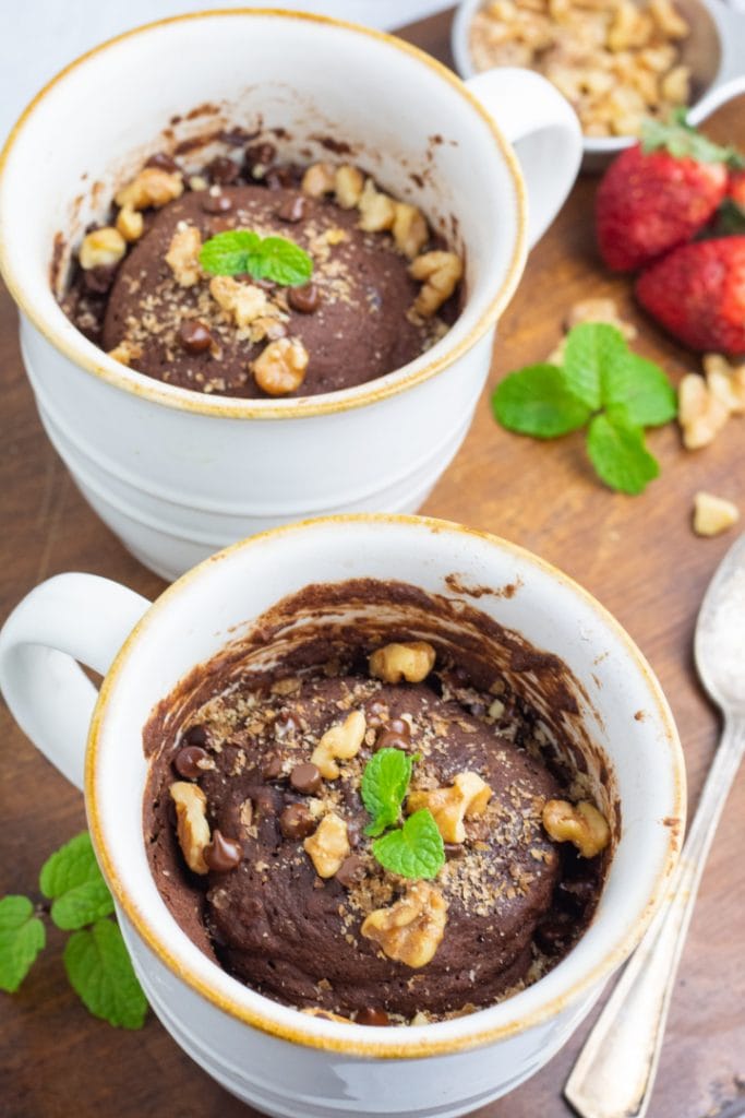 two white coffee mugs filled with chocolate mug cake topped with mint leaf