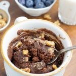 white coffee mug with chocolate cake on wooden board with blueberries in background