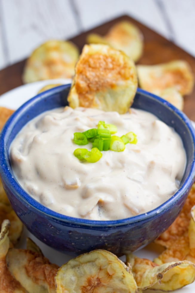 bright blue bowl with vegan french onion dip and potato chips