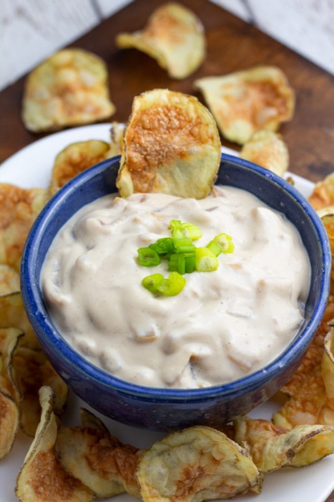 close up of vegan dip in blue bowl with a potato chip in it