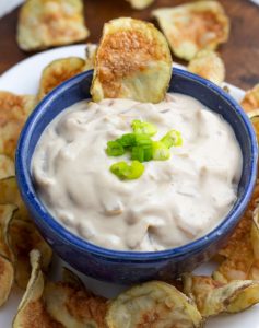 close up of vegan dip in blue bowl with a potato chip in it