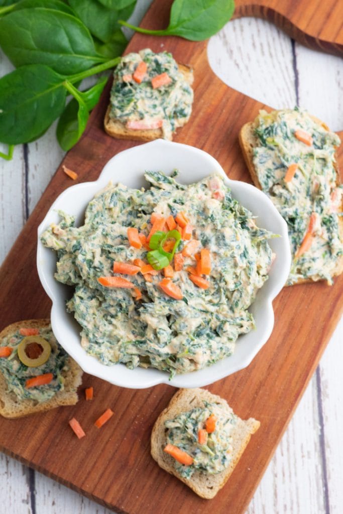 overhead photo of vegan spinach dip in white bowl with crackers