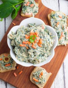 overhead photo of vegan spinach dip in white bowl with crackers
