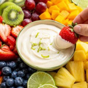 platter of fresh fruit with a bowl of creamy lime dip in the middle.