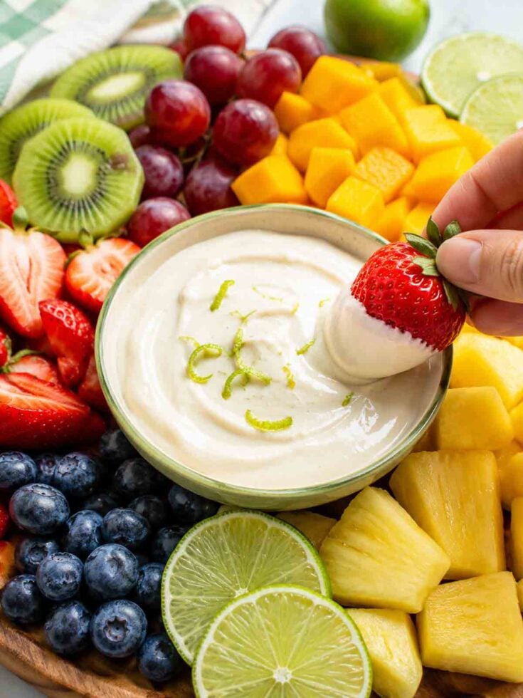 platter of fresh fruit with a bowl of creamy lime dip in the middle.
