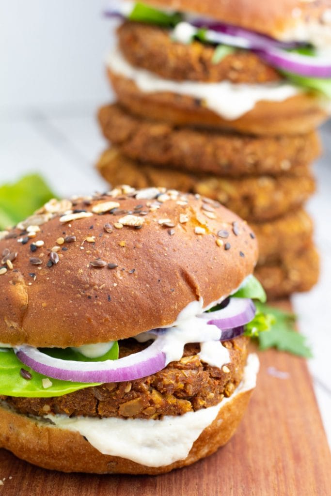 chickpea burger with lettuce, onions, vegan mayo and chickpea patties stacked in background