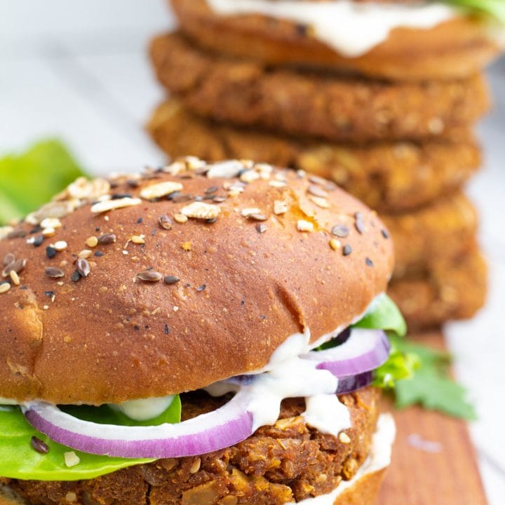 chickpea burger with lettuce, onions, vegan mayo and chickpea patties stacked in background