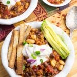 overhead shot of mexican soup in white bowls with avocado