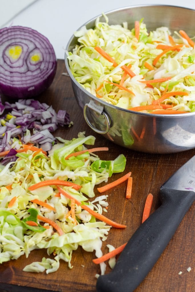 slaw chopped up on wooden cutting board with red onion