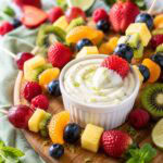 colorful fruit skewers on a platter with a bowl of fruit lime sauce.