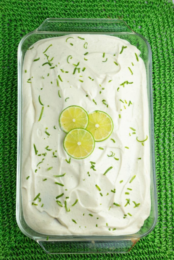 overhead shot of clear baking dish of lime cake topped with 3 lime slices