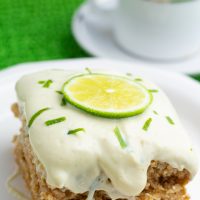 close up of lime cake with white lime frosting and topped with lime slice
