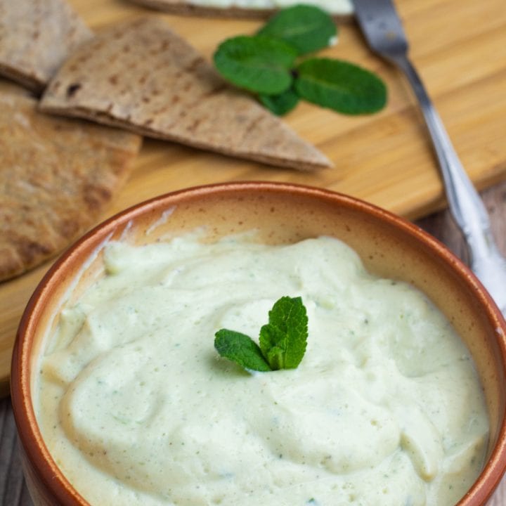 Tzatziki sauce in brown bowl with pita triangles
