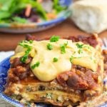 vegan lasagna topped with cashew cheese close up with salad and bread in background