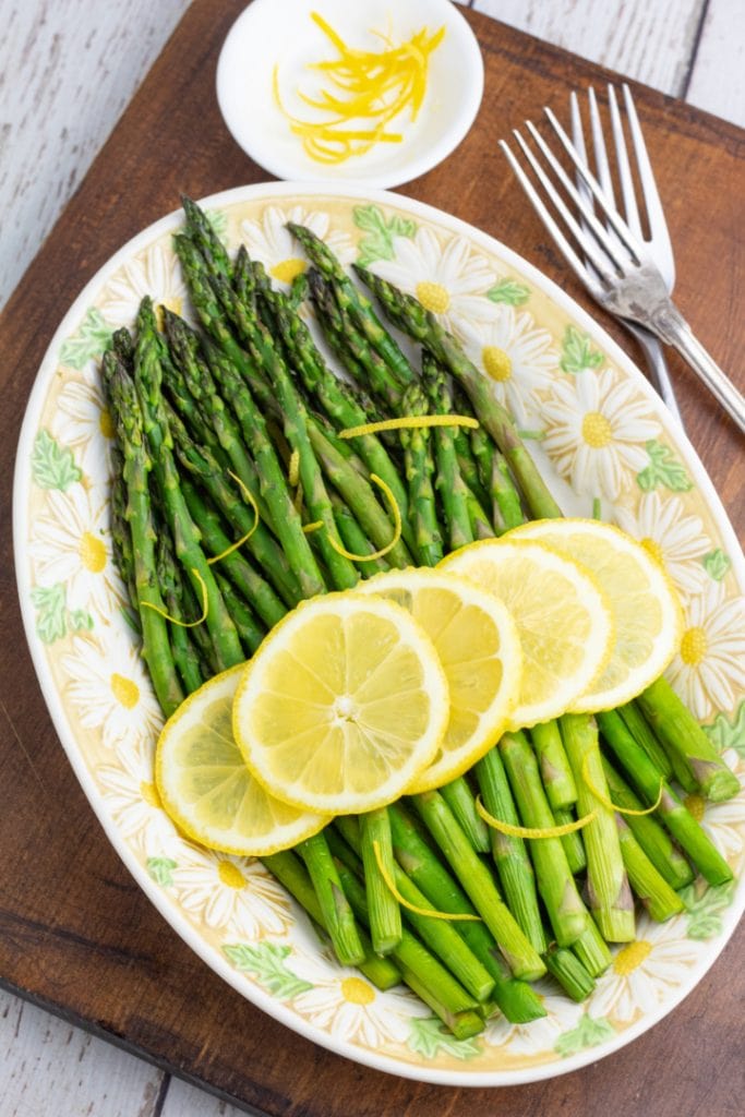 air fryer asparagus in oval plater topped with lemon slices