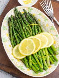 air fryer asparagus in oval plater topped with lemon slices