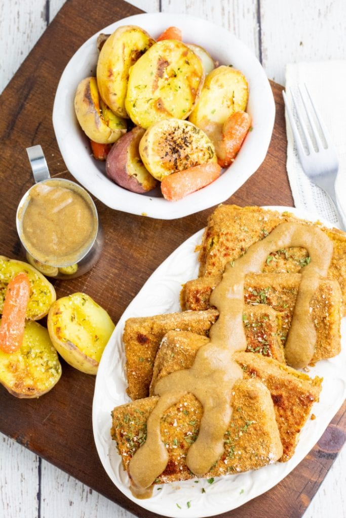 wooden board with platter of baked tofu and roasted potatoes and carrots