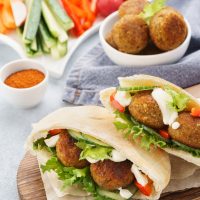 Healthy vegetarian falafel pita with fresh vegetables, lettuce and sauce.
