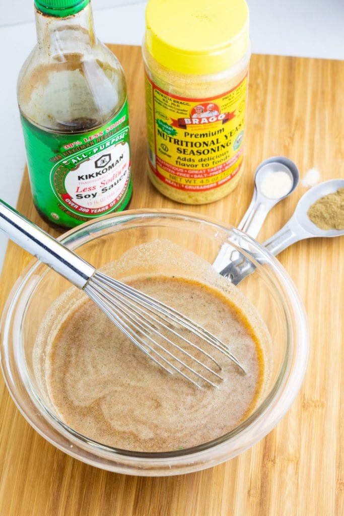 clear mixing bowl with gravy ingredients and whisk with bottle of soy sauce and meassuring spoons