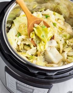 instant pot full of cooked cabbage with a wooden spoon