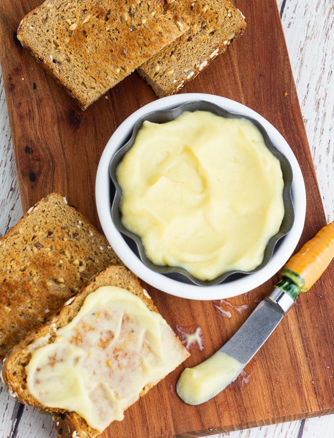 overhead photo of bowl of vegan butter with slices of toast on wooden cutting board