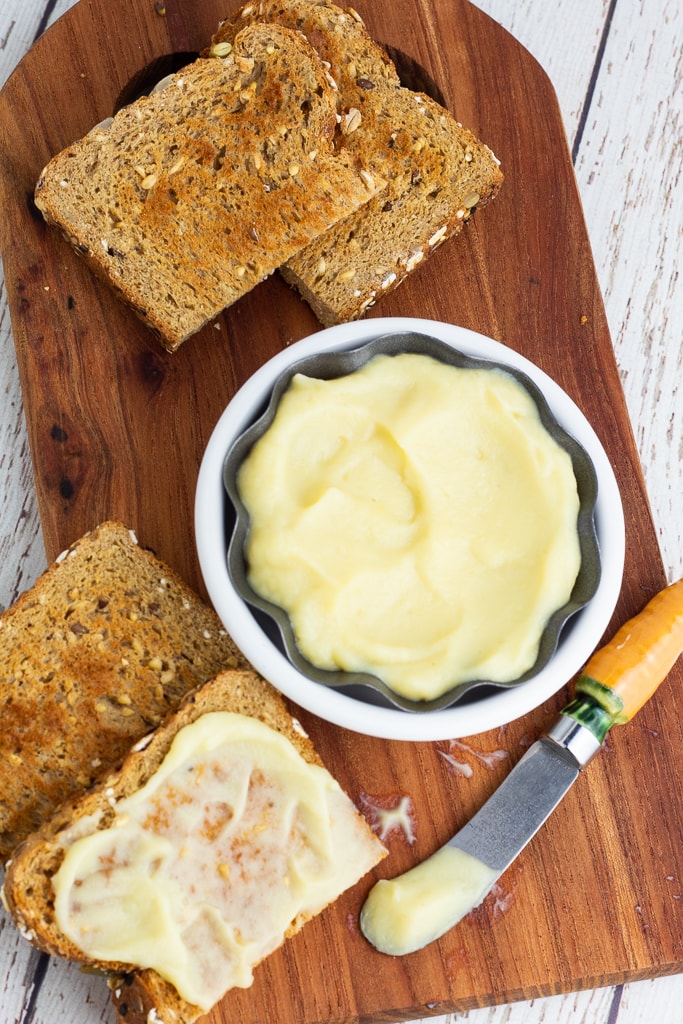 overhead photo of bowl of vegan butter with slices of toast on wooden cutting board