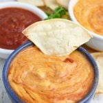 blue bowl of vegan queso with corn chip
