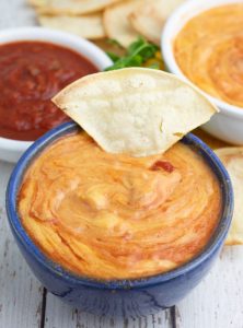 blue bowl of vegan queso with corn chip