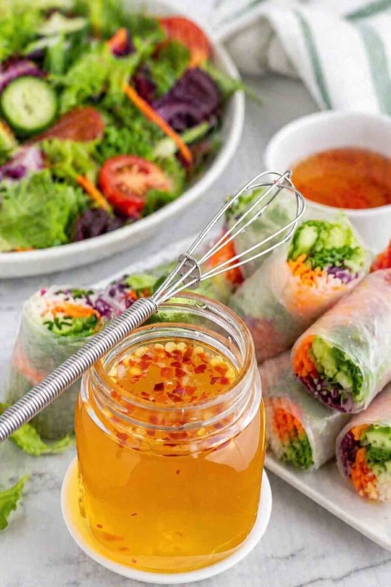 oil-free Thai vinegar sauce in a jar with garden rolls and salad in background.