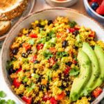 big bowl filled with loaded tofu scramble with avocado slices.