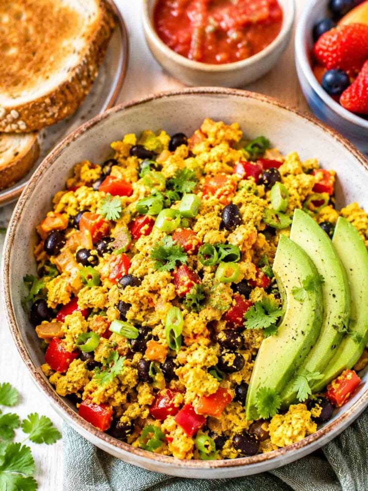 big bowl filled with loaded tofu scramble with avocado slices.